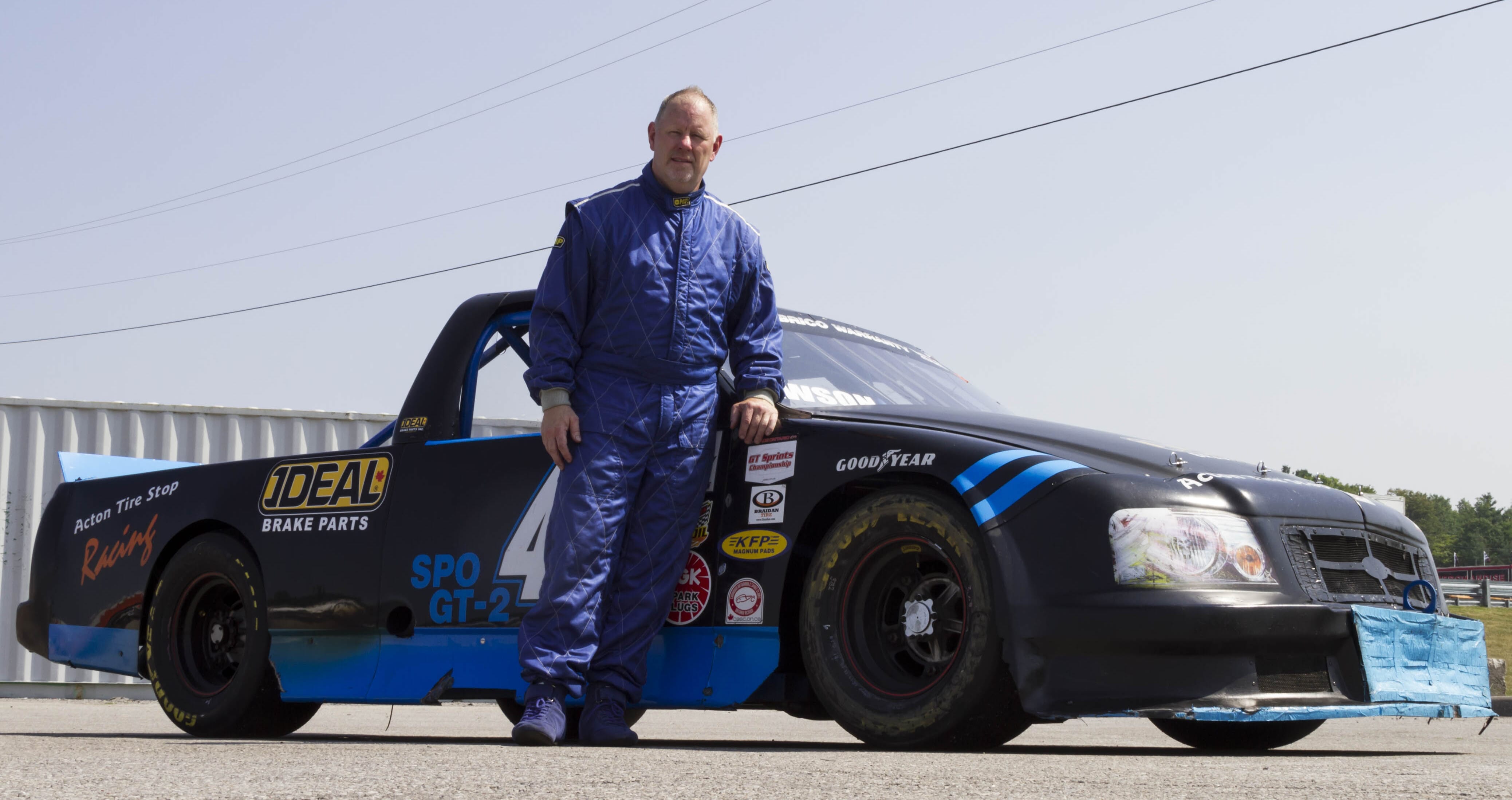 Chris standing with his custom F-150 looking for the checkered flag.